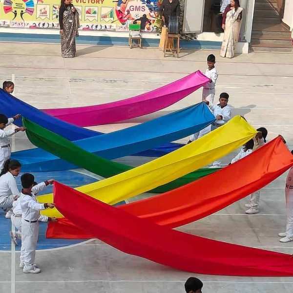 Vibrant kids participating in outdoor activity with colorful fabrics at Gurukul Montessori School Prayagraj.