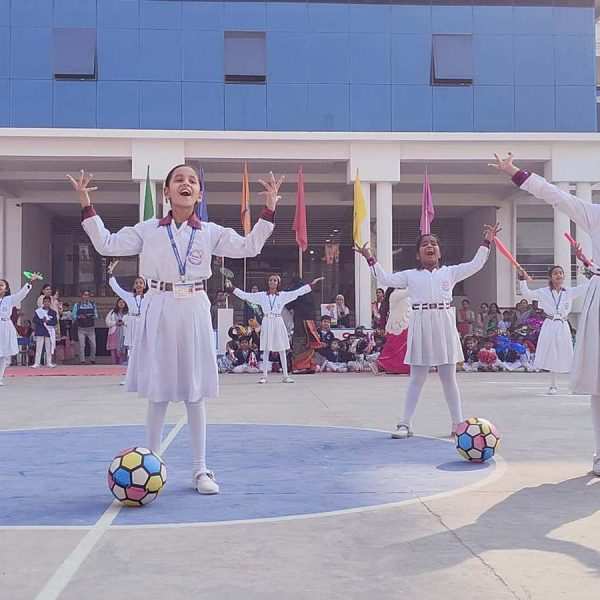 Cheerful children in school uniforms dancing on the school playground with colorful crowd in the background.